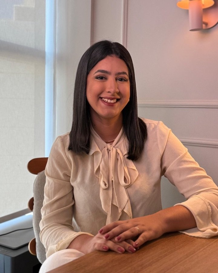 Rafaella Rodrigues, psicóloga infantojuvenil, sorrindo à mesa do consultório